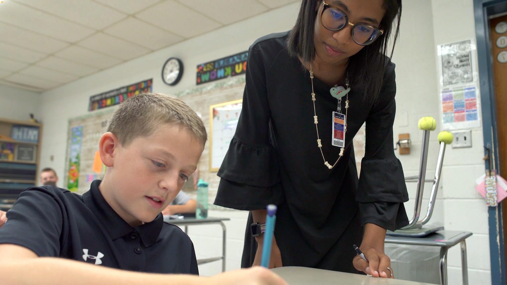 Education teacher in class with grade school student