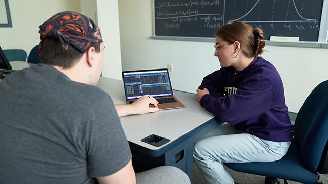 Mathematics students sharing laptop